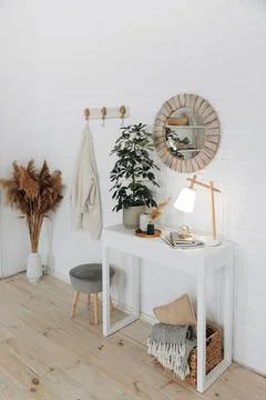 Console table with a potted plant, a table lamp and a round mirror in a wooden Stock Photos