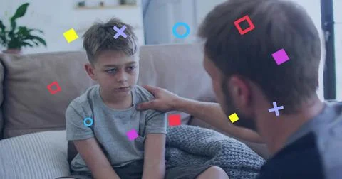 Consoling man placing hand on boy wearing light gray t-shirt on beige couch, Stock Photos