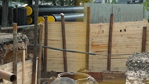 Constructing a deep excavation site with wooden supports and pipes. The setting Stockbeeldmateriaal 344676200