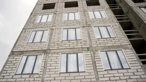 Constructing residential building with new windows under grey sky Stock Photos