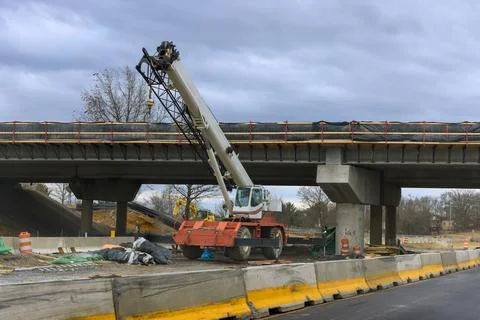 Construction activity with crane in progress below bridge in busy area Stock Photos