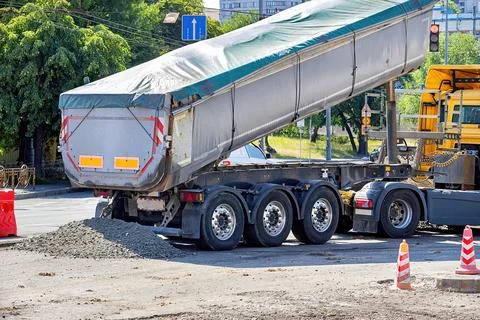 Construction activity showcases a truck unloading gravel at a busy intersec.. Stock Photos
