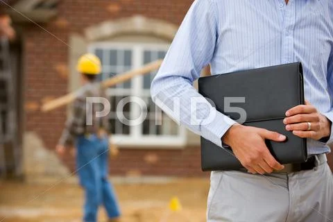 Construction: agent holding portfolio with worker in background Stock Photos
