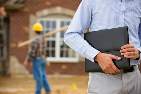 Construction: agent holding portfolio with worker in background Stock Photos