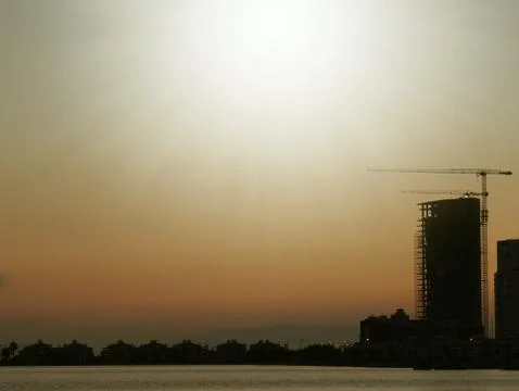 Construction and sky-scraper building and crane against colorful sky with sun Stock Photos