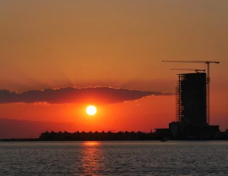 Construction and sky-scraper building and crane against colorful sky with sun Stock Photos