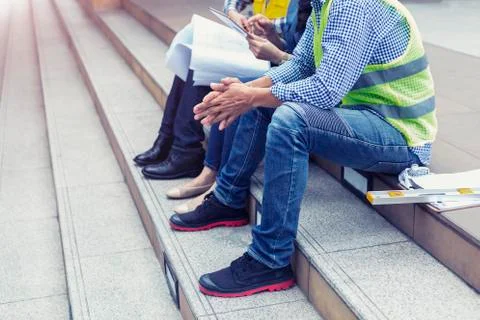 Construction background concept. Engineering worker sitting on stair to talki Stock Photos