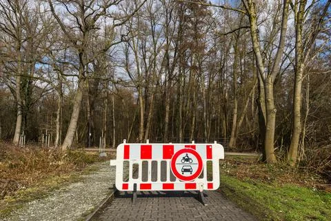 Construction barrier blocks path in forest area during daytime Stock-Fotos