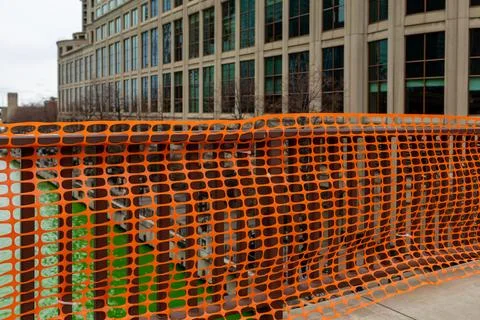 Construction barrier is placed around building near water on a cloudy day i.. Stockfoto's