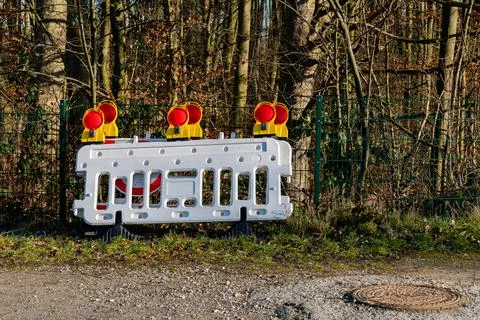 Construction barrier with warning lights placed near a wooded area Stock Photos