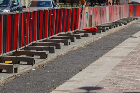 Construction barriers in bright red line a street, indicating ongoing develop Stock Photos