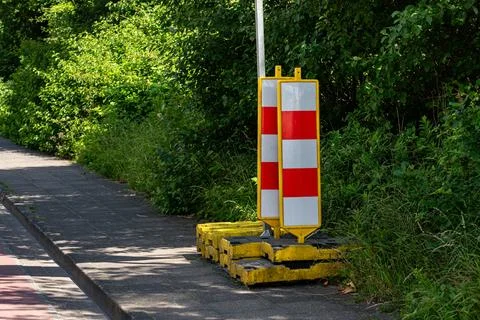 Construction barriers placed along a sidewalk in a green area Stock Photos