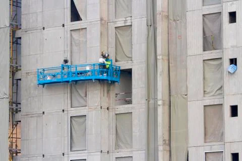 Construction baskets blue next to the building with workers Stock Photos