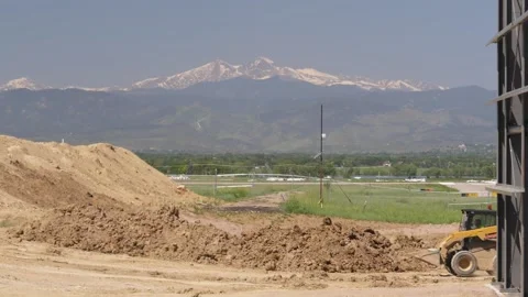 Construction bobcat passes with Rocky mountains Stock Footage 166331357