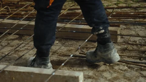 Construction boots walking across steel rebar grid foundation Stock Footage 331677948