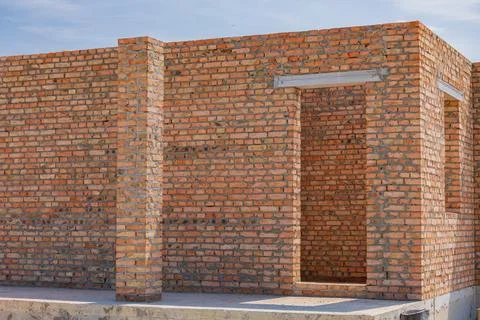 Construction of a brick structure is underway, showcasing raw, unfinished w.. 库存照片