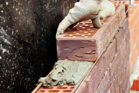 Construction of a brick wall. Bricklaying. A worker builds a brick wall Stock Photos