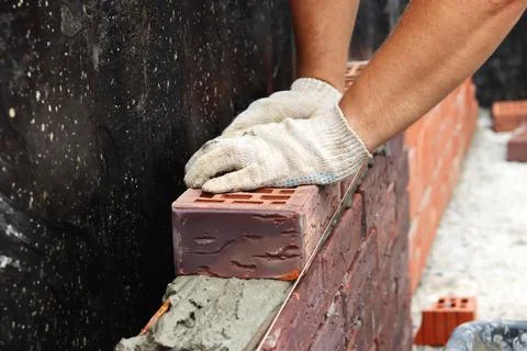 Construction of a brick wall. Bricklaying. A worker builds a brick wall Stock Photos