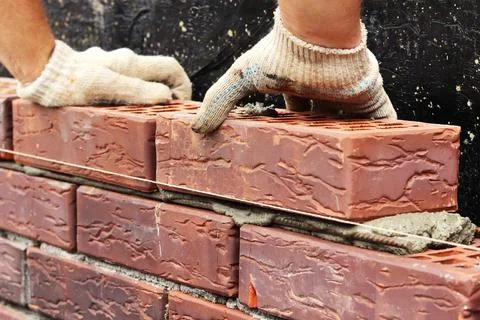 Construction of a brick wall. Bricklaying. A worker builds a brick wall Stock Photos