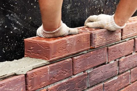 Construction of a brick wall. Bricklaying. A worker builds a brick wall Stock Photos