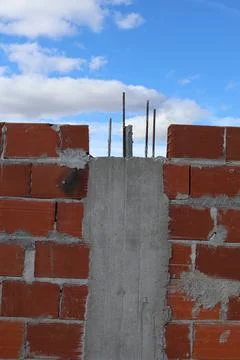 Construction of a brick wall with concrete and blue sky background Stock Photos