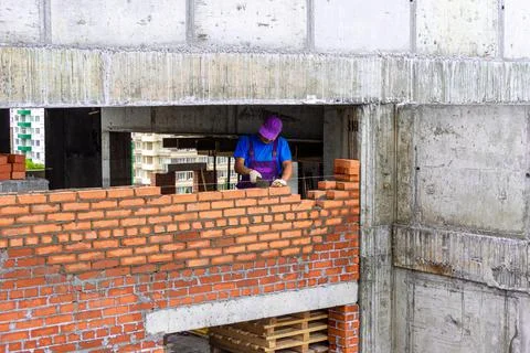 Construction of a brick wall in a monolithic frame building, a bricklayer lays Stock Photos