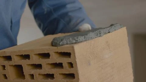 Construction of brick wall. Trowel spreading cement on bricks. Worker spreads Foto stock