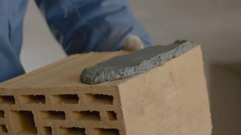 Construction of brick wall. Trowel spreading cement on bricks. Worker spreads Foto stock