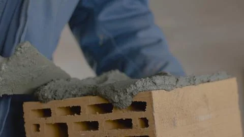 Construction of brick wall. Trowel spreading cement on bricks. Worker spreads 스톡 사진