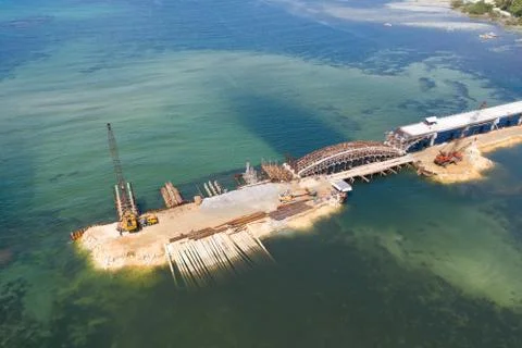 Construction of a bridge across the bay. Construction equipment on the bridge Stock Photos