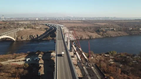 Construction of a bridge across the river. Heavy traffic on the bridge. Stock Footage 196390126