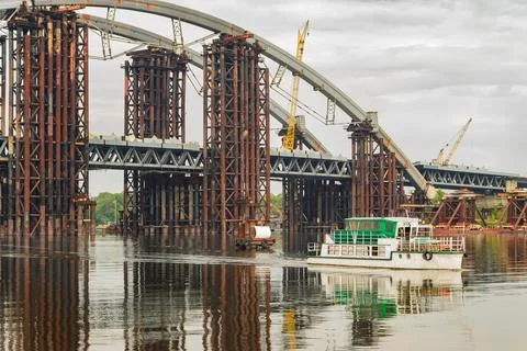 Construction of the bridge. A bridge being built across a wide river with a s Stock Photos