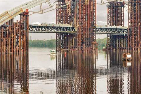 Construction of the bridge. A bridge being built across a wide river with a s Stock Photos