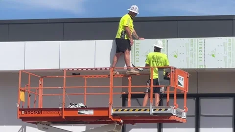 Construction builders removing newly installed exterior tiles on a building Stock Footage 332378987