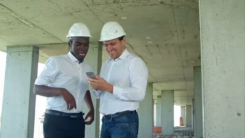 Construction builders smiling while using smartphone at site Stock Footage 82802468