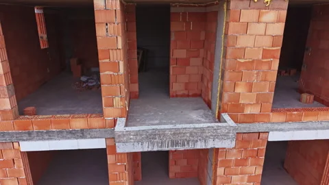 Construction of a building with red bricks in process during daytime in an urban Stock Footage 337948741