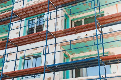 Construction of a building with scaffolding and open windows in a busy city.. Stock Photos