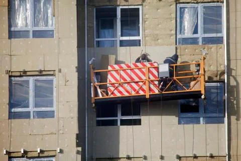 Construction of the building. Workers warm outside walls panels. Stock Photos