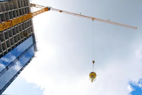 Construction of buildings: the lifting crane bears a bucket with concrete, ag Stock Photos