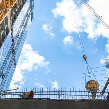 Construction of buildings: the lifting crane bears a bucket with concrete, ag Stock Photos