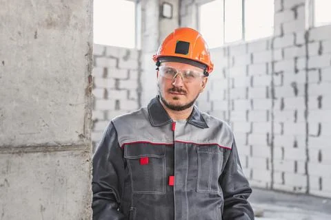 Construction caucasian worker in hard hat, overalls and safety glasses at Stock Photos