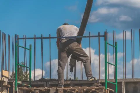 The construction, cement pouring with machine into the frame of the house, wo Photos