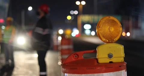 Construction cone deviating the traffic with construction workers on the back Stock Footage 156940005