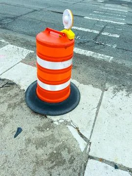Construction cone stands on sidewalk as workers prepare street in city at m.. Stock-Fotos