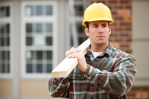 Construction: contractor carrying a beam Stock Photos
