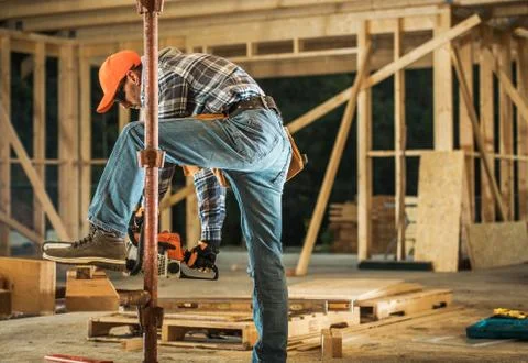 Construction Contractor with Chainsaw Preparing Wood Elements Foto stock