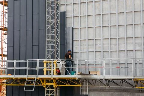 Construction cradle with a builder on the wall of an apartment building Stock Photos