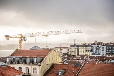 Construction crane above Lisbon rooftops with Cristo Rei 스톡 사진