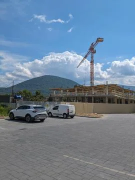 Construction crane against the backdrop of mountains and cloudy sky. Stock Photos