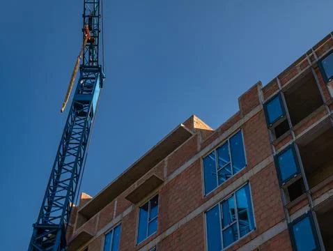 Construction crane against the background of a building under construction. Stock Photos
